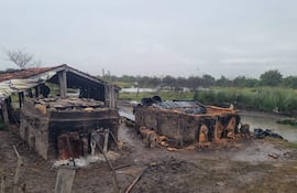 Estructuras dañadas en un paisaje rural, con barro y vegetación tras la crecida del río Tebicuary, sin personas presentes.