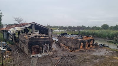 Estructuras dañadas en un paisaje rural, con barro y vegetación tras la crecida del río Tebicuary, sin personas presentes.