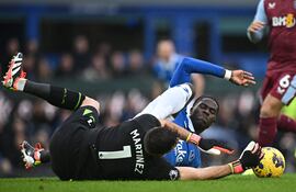 El portero argentino del Aston Villa #01 Emiliano Martínez (L) resulta herido mientras el centrocampista belga nacido en Senegal del Everton #08 Amadou Onana (R) se desliza para tratar de conseguir el balón regalando una falta durante el partido de fútbol de la Premier League inglesa entre Everton y Aston Villa en Goodison Park en Liverpool, noroeste de Inglaterra, el 14 de enero de 2024.
