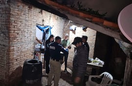 Un policía con uniforme interactúa con una mujer de suéter negro, mientras otros observan la escena en un ambiente sombrío.