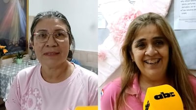 Albina Cardozo y Dorian Martínez sonríen, ambas con camisetas rosas, en un entorno con decoraciones sencillas y un cuadro religioso.