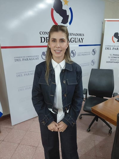 Norma Zárate en chaqueta de mezclilla oscura y camisa blanca, frente a un banner del Consejo de Gobernadores del Paraguay.