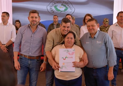 El presidente, Santiago Peña, en compañía del vicepresidente, Pedro Alliana, entregan uno de los título de propiedad a familiar de la zona.