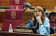 Senadora Celeste Amarilla, con cabello largo y vestido de puntos, escucha atentamente en un recinto legislativo.