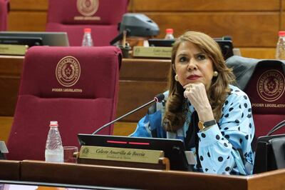 Senadora Celeste Amarilla, con cabello largo y vestido de puntos, escucha atentamente en un recinto legislativo.