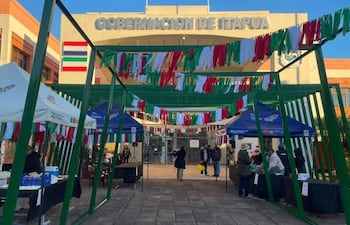 Carpas de colores en la Gobernación de Itapúa, con personas interactuando y ofreciendo comidas típicas en un ambiente festivo.