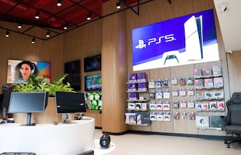 Nissei. Varias pantallas y monitores en una tienda de videojuegos con accesorios organizados en estanterías y plantas decorativas.