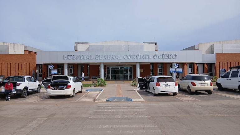 Exterior del Hospital General de Coronel Oviedo, con vehículos estacionados y ambiente despejado.