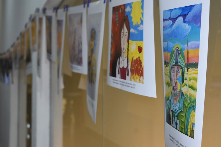 Obras de arte expuestas en un ambiente interior, incluyendo retrato de soldado en un evento cultural.