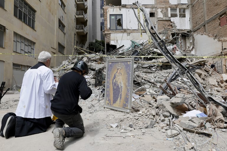 FOTODELDÍA AME9126. PEREIRA (COLOMBIA), 14/08/2026.- El padre Nelson Giraldo Mejía ora por las víctimas del terremoto de magnitud 7,4 ocurrido el pasado lunes, frente a los escombros del edificio Santiago Londoño, con una réplica de la Virgen de Nuestra Señora de la Pobreza, este viernes en Pereira. (Colombia). EFE/ Carlos Ortega