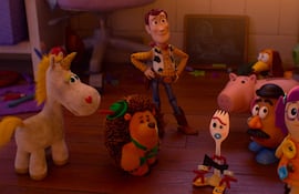Muñeco de vaquero interactúa con un unicornio, erizo y otros juguetes en un ambiente acogedor y colorido.