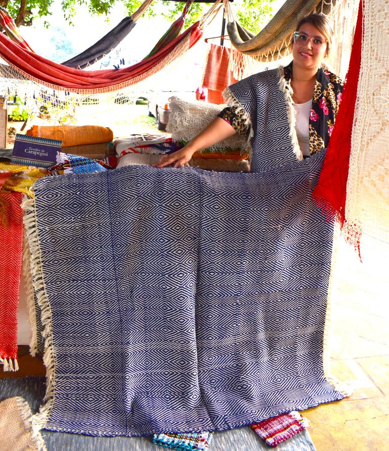 Licia Medina, hija de la artesana Mirta Orihuela de la compañía Espartilla, exhibe una de las colchas confeccionada en el telar de cuatro lisos.
