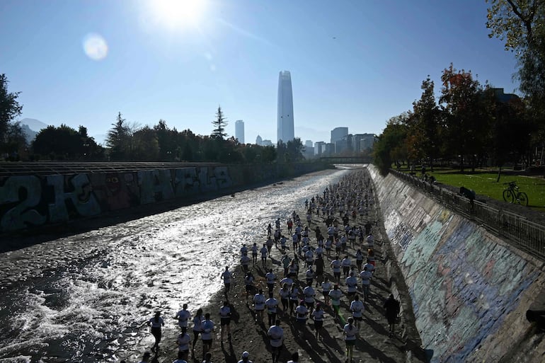 Corredores participan en una carrera a lo largo de las riberas del río Mapocho en Santiago el 17 de mayo de 2026. Las aguas contaminadas del río Mapocho, que atraviesa la capital chilena, alguna vez avergonzaron a los residentes, quienes ahora disfrutan de él tras su limpieza.