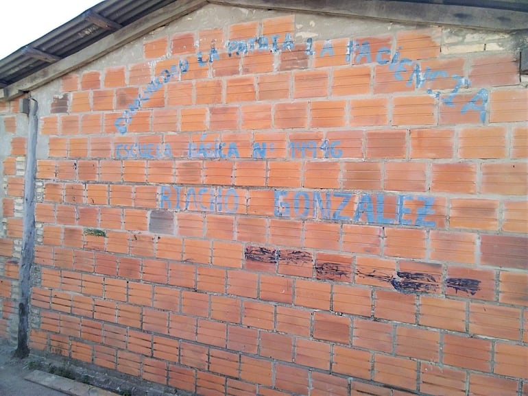 Pared de ladrillos naranjas con un mural que identifica la Escuela Básica N° 14946 Riacho González.