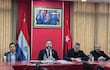 Rodrigo Nicora y otros diputados en traje negro sentados en mesa con banderas de Paraguay y Turquía, revisando documentos.