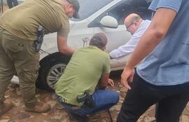 Agentes de Control de Automores verifcan el auto Kia Soluto blanco, que fue ubicado en la casa ocupada por el presunto lider de la banda de robacoches. El vehículo presentaba varios impactos de bala.