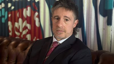 Rogelio Ortuzar sentado en un entorno moderno, vestido con traje oscuro y corbata de colores, con expresión reflexiva.