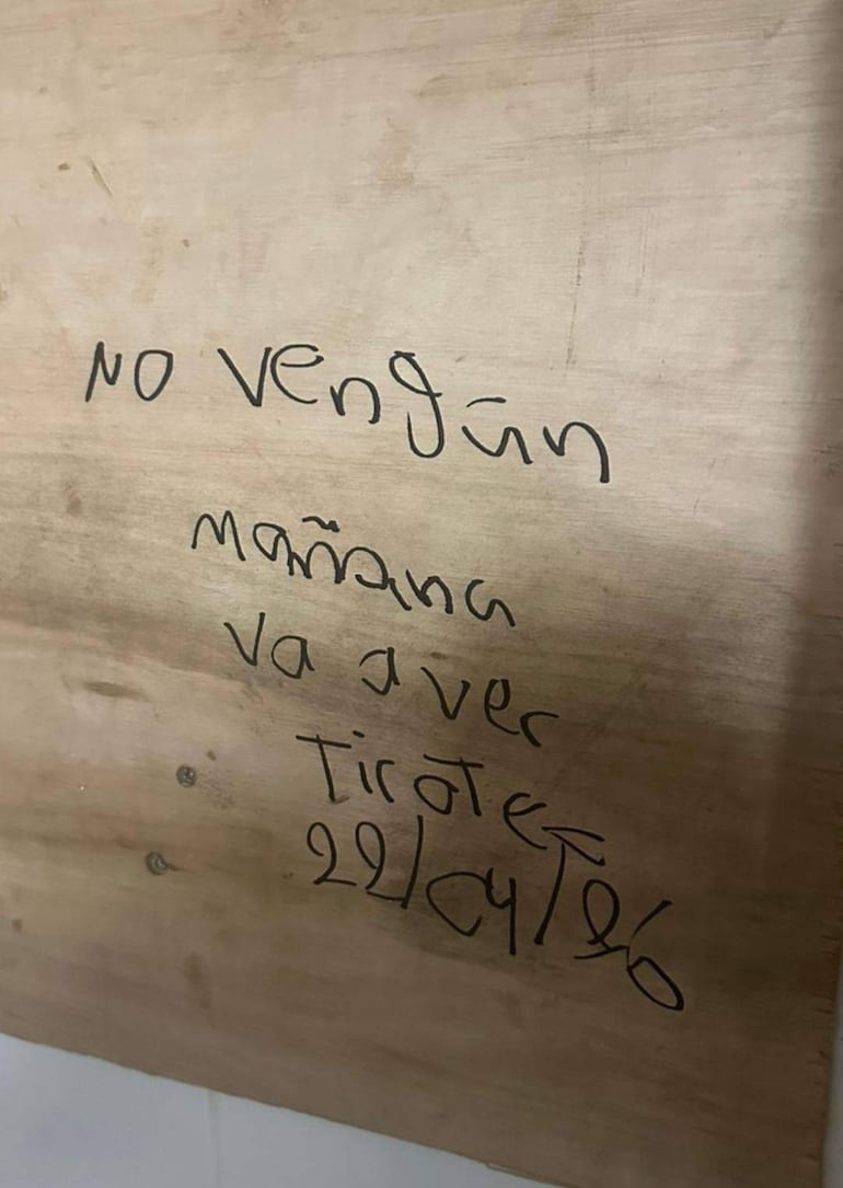 Trozo de madera con texto manuscrito que advierte sobre un tiroteo.
