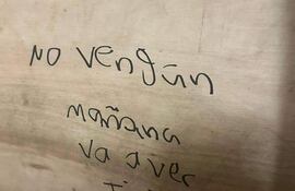 Trozo de madera con texto manuscrito que advierte sobre un tiroteo.