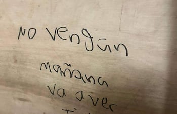 Trozo de madera con texto manuscrito que advierte sobre un tiroteo.