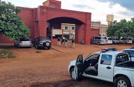 Policías uniformados conversan en la entrada de un edificio, mientras dos camionetas del Gobierno del Paraguay están estacionadas.