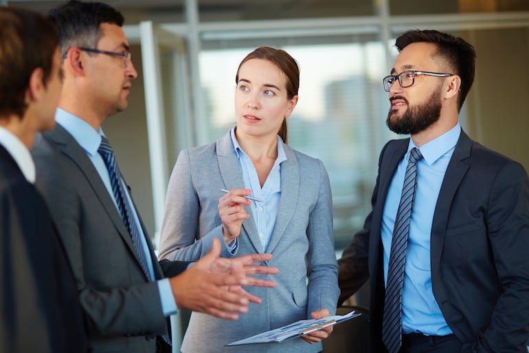 Elegantes socios comerciales observando a un colega en una reunión.