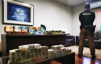 Un agente de Senad junto al millón y medio de dólares no declarados en los libros contables y que fueron hallados en una oficina, del nivel superior, del local de Panorama Cambios, cuya sucursal intervenida está en Villa Morra.