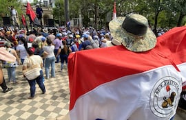 AME2961. ASUNCIÓN (PARAGUAY), 11/03/2026.- Una persona sostiene una bandera durante una manifestación en contra a la reforma de jubilaciones este miércoles, en Asunción (Paraguay). Los gremios de docentes en Paraguay lideran una segunda jornada de protestas en contra de una reforma del sistema de jubilaciones y pensiones del sector público, conocido como la 'caja fiscal', que el Senado discute en medio de marchas y de una fuerte custodia policial. EFE/ Ron González