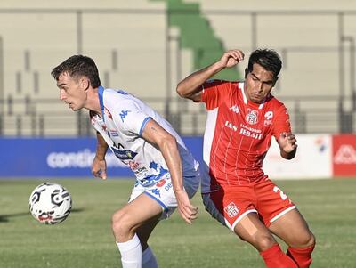 El volante de Nacional, Juan Alfaro, cubre con el cuerpo el esférico ante la llegada del volante de General Caballero PJC, Pablo Ayala.