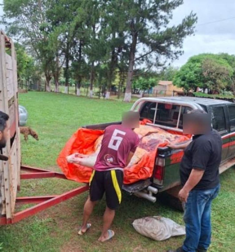 Hombre en camiseta burdeos con el número 6, ayudado por otros dos, cargan un objeto envuelto en manta naranja.