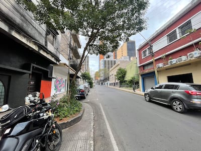 Calle urbana vacía, con motocicleta negra estacionada y edificios, bajo un cielo nublado.