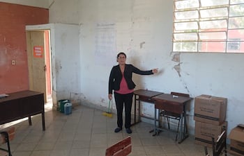 La directora, María Victoria Mendoza, mostrando una enorme fisura en la pared de la sala del 7mo grado.