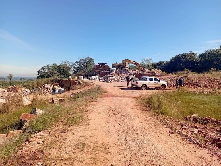 Terreno rural en Emboscada, con un camino de tierra, una excavadora en el fondo y un par de individuos junto a una camioneta blanca.