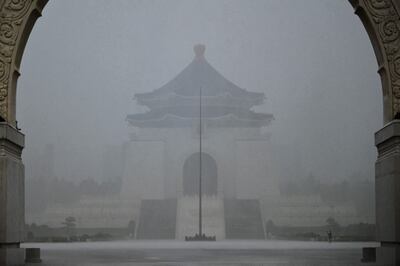 Un visitante (abajo a la derecha) toma fotografías frente al Salón Conmemorativo de Chiang Kai-shek bajo una fuerte lluvia debido a los patrones climáticos causados por el tifón Gaemi en Taipei.