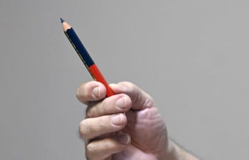 William Wilka sostiene un lápiz bicolor, mostrando que eligió el color azul, el de la libertad, para esbozar la proclama libertaria que el Gral. Andrés Rodríguez leyó y se emitió por radio aquel 2 y 3 de febrero de 1989.