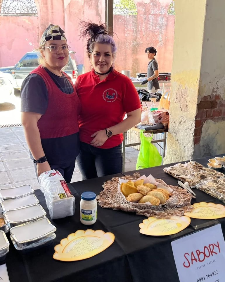 dos mujeres posando frente a una mesa de comidas