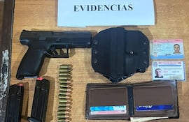 Escritorio con una pistola negra, cargadores y documentos de identidad en un entorno policial.