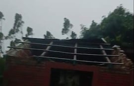Estructura de ladrillo con techo desmoronado y vegetación cercana, en un entorno rural y nublado.