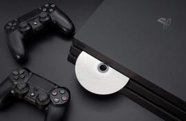 Consola PlayStation en la parte inferior central con disco insertado, rodeada de dos controladores en un ambiente oscuro.