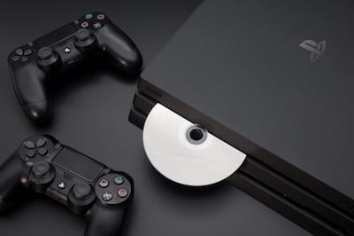 Consola PlayStation en la parte inferior central con disco insertado, rodeada de dos controladores en un ambiente oscuro.