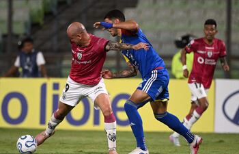 El delantero paraguayo del Independiente del Valle, Carlos González, y el defensa de Universidad Central, Williams Velásquez, luchan por el balón durante el partido de fútbol de la fase de grupos de la Copa Libertadores entre el Universidad Central de Venezuela y el Independiente del Valle de Ecuador en el estadio Olímpico de la UCV en Caracas