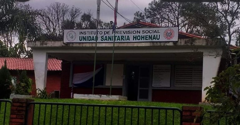 Fachada del Instituto de Previsión Social en Hohenau, con cartel visible, reja y jardín alrededor en un día nublado.