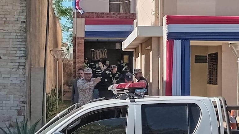 Grupo de personas gesticulando en manifestación con decoraciones rojas, blancas y azules, y presencia de seguridad.