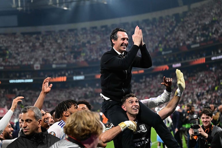 El entrenador español Unai Emery celebra en los hombros del Dibu Martínez el título.