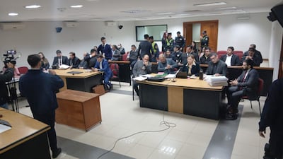 Hombres y mujeres en sala judicial, atentos y tomando notas, en ambiente tenso durante la suspensión del juicio.