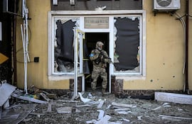 Un miembro de la línea de defensa de Ucrania frente a un edificio devastado por la guerra con Rusia, en la región de Kiev.