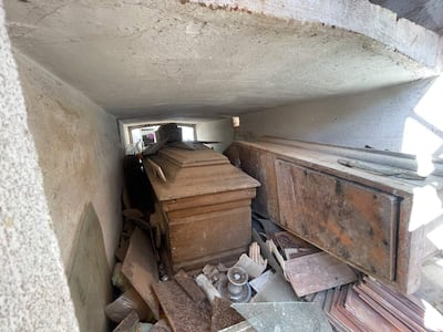 Ataúdes de madera en un espacio desordenado junto a restos de materiales de construcción en un ambiente cerrado.