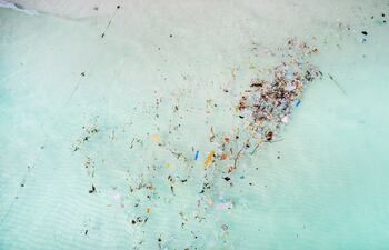 Vista aérea de las aguas oceánicas contaminadas con desechos plásticos. Imagen ilustrativa.