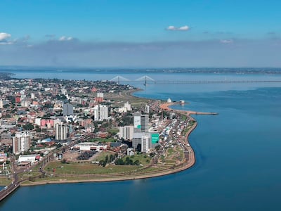 Vista aérea de Ciudad del Este, mostrando edificios y el Puente Internacional de la Amistad bajo un cielo despejado.