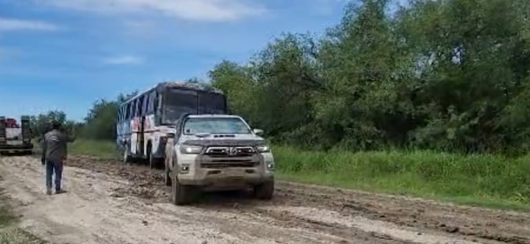 Un conductor a bordo de una camioneta todo terreno, ayuda a sacar del barro al colectivo.